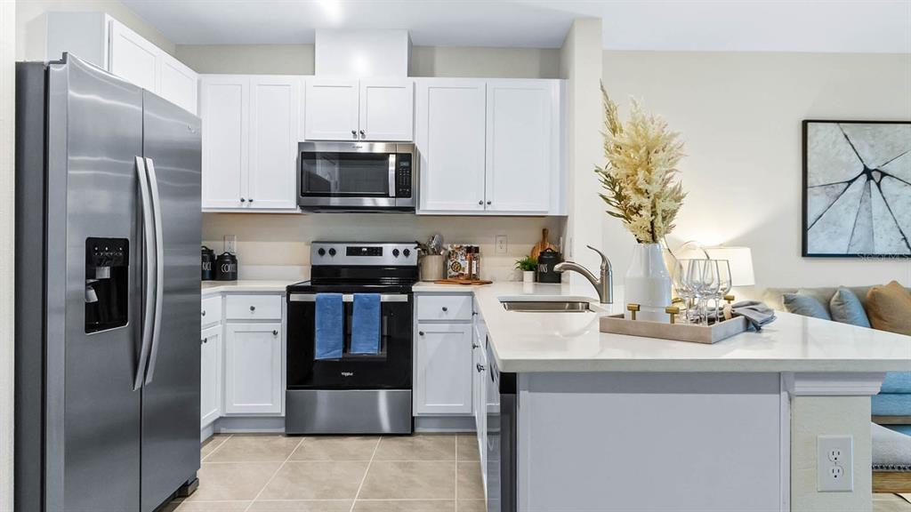 31191 Midnight Sun Way Wesley Chapel, FL 33545 - Photo 8 of 22 a kitchen with a sink stainless steel appliances and white cabinets