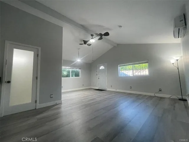 an empty room with wooden floor ceiling fan and windows