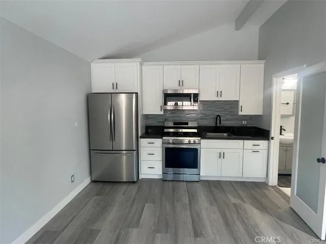 a kitchen with granite countertop a refrigerator and a stove top oven