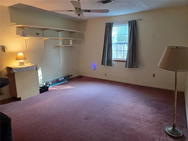 an empty room with windows and fan