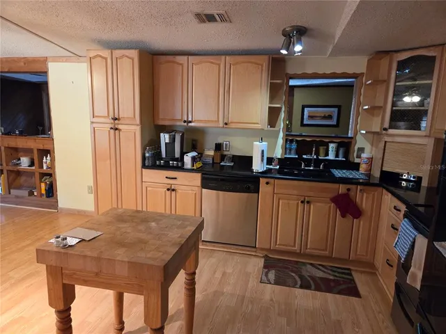 a kitchen with granite countertop a stove a sink dishwasher and a refrigerator with wooden floor