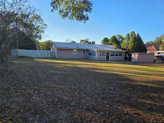 a view of a house with a yard and a large tree