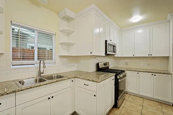 a kitchen with granite countertop white cabinets and a sink