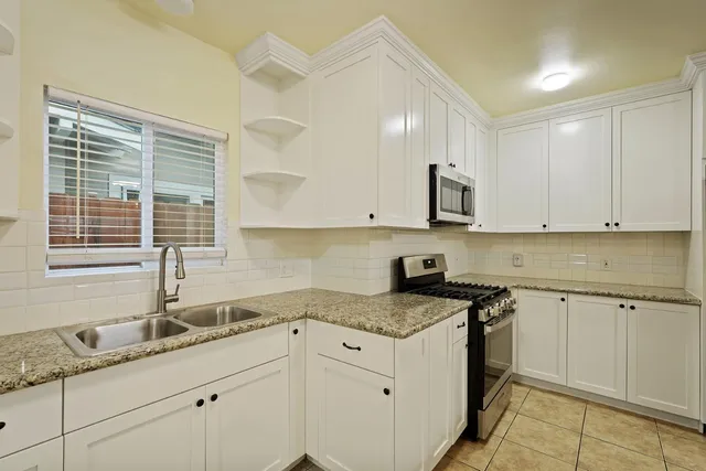 a kitchen with granite countertop white cabinets and a sink