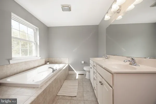 a spacious bathroom with a granite countertop sink and a bathtub