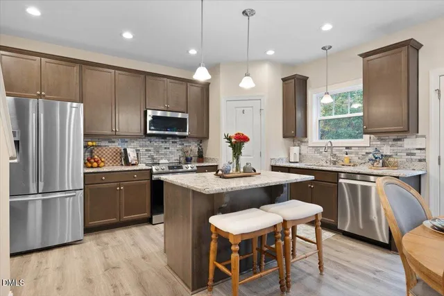 a kitchen with stainless steel appliances granite countertop a sink refrigerator and microwave