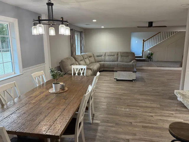a living room with couches chairs and kitchen view with wooden floor