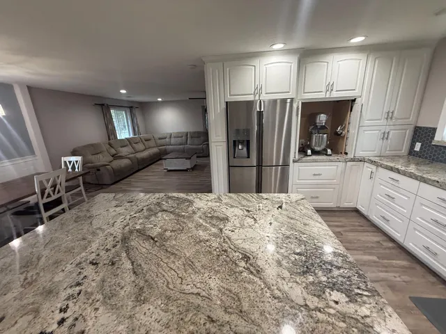 a kitchen with stainless steel appliances kitchen island granite countertop a refrigerator and a stove top oven