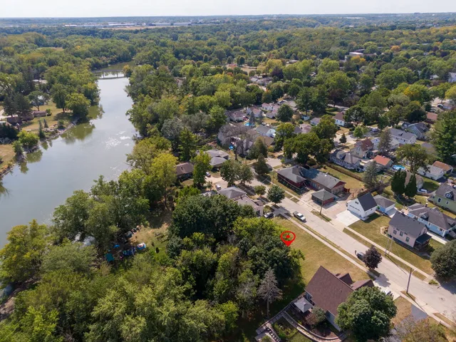 an aerial view of city and lake with trees