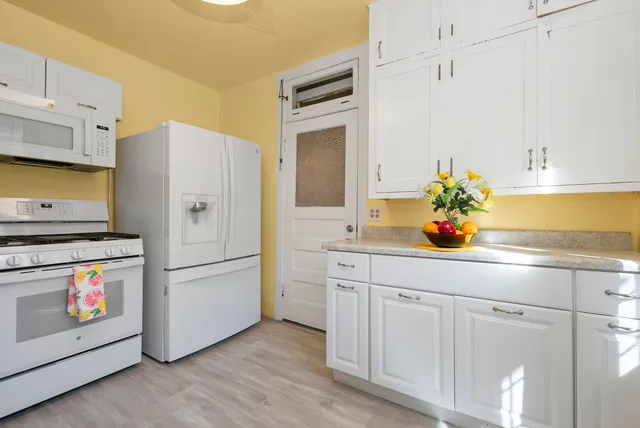 a kitchen with stainless steel appliances white cabinets and wooden floor
