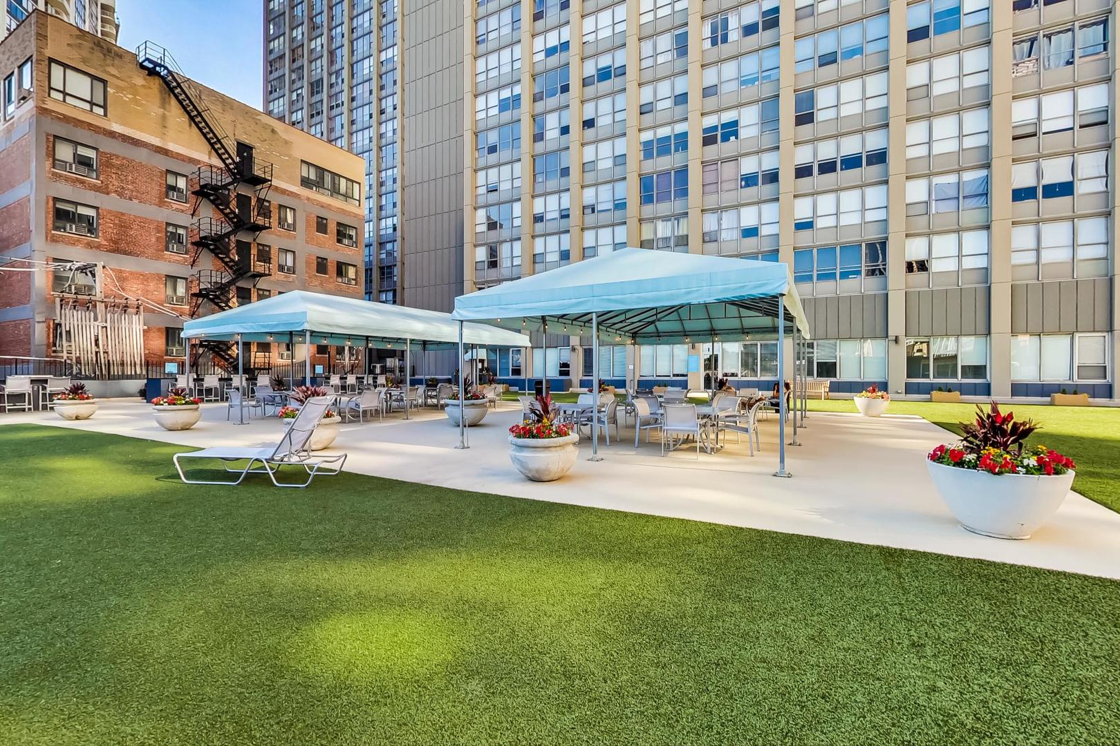 655 West Irving Park Road, Unit 5405 Chicago, IL 60613 - Photo 19 of 31 a patio with tables and chairs and a umbrella