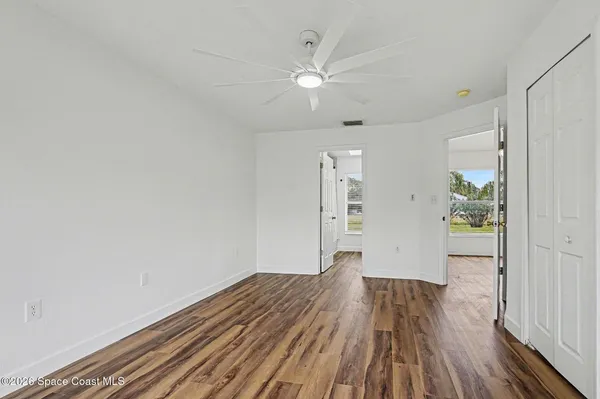 a view of empty room with wooden floor and fan