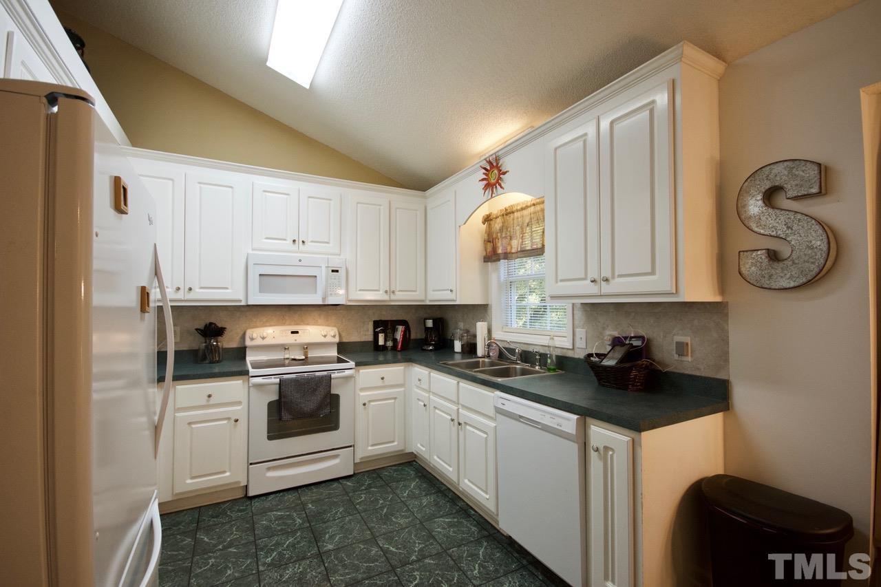 128 Forest Ridge Drive Willow Spring, NC 27592 - Photo 7 of 25 a kitchen with white cabinets a sink dishwasher and a stove with wooden floor