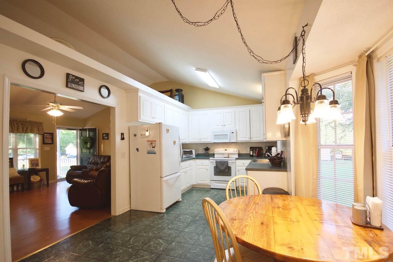 128 Forest Ridge Drive Willow Spring, NC 27592 - Photo 8 of 25 a kitchen with stainless steel appliances kitchen island granite countertop a refrigerator a stove and a dining table with wooden floor