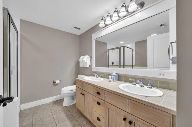 a bathroom with a double vanity sink mirror and toilet