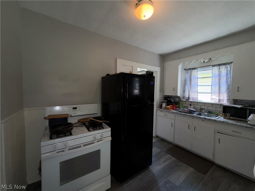 18017 Olympia Road Cleveland, OH 44112 - Photo 18 of 34 Kitchen featuring wood-finish flooring, white cabinetry, a stainless steel sink, and a tiled backsplash