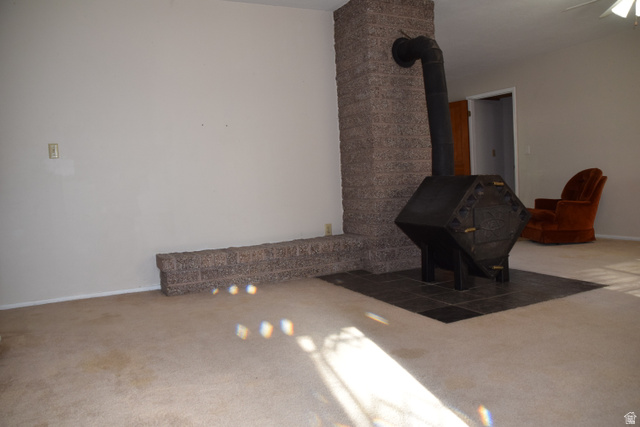 4265 South 4000 W Road Delta, UT 84624 - Photo 25 of 32 Stone-finish fireplace with a black wood-burning stove and a tiled hearth