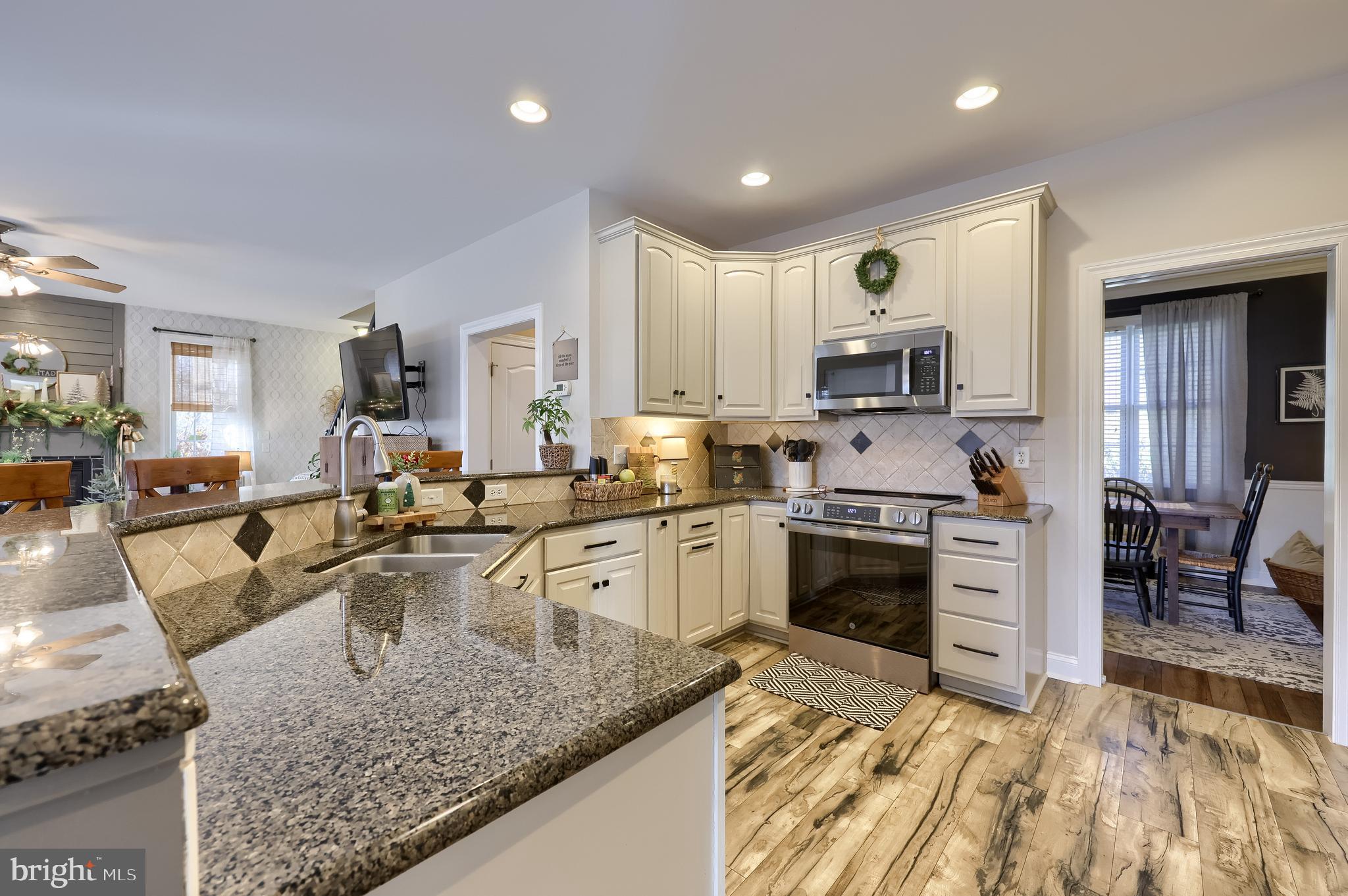 471 Shenks Ferry Road Conestoga, PA 17516 - Photo 21 of 105 a kitchen with stainless steel appliances granite countertop a stove top oven a sink dishwasher a dining table and chairs with wooden floor