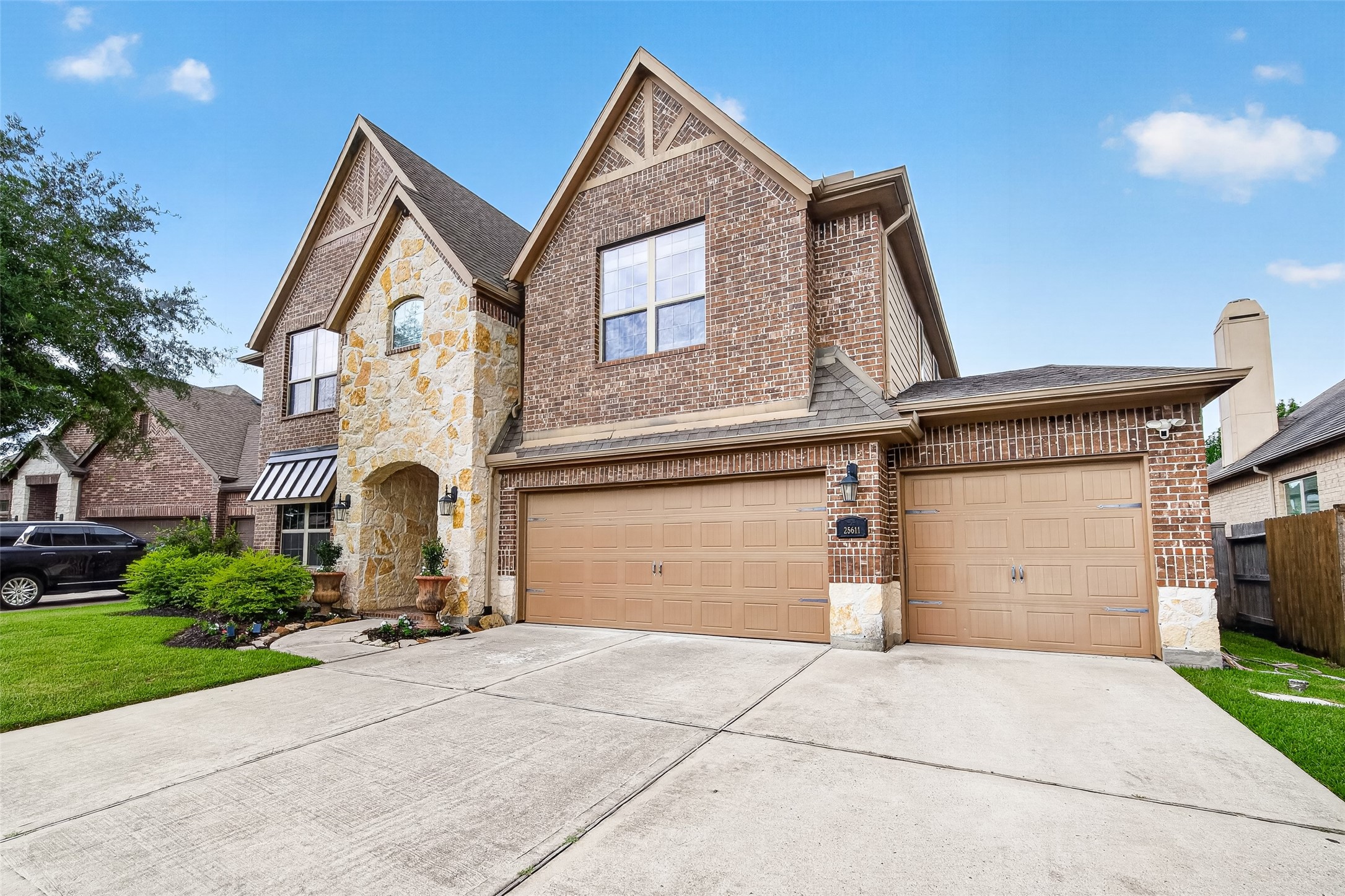 25611 Ellis Ridge Court Katy, TX 77494 - Photo 3 of 49 This two-story home features a combination of brick and stone exterior with a spacious three-car garage. The front yard is well-maintained with a neat lawn and landscaped garden. The driveway is wide, offering ample parking space.