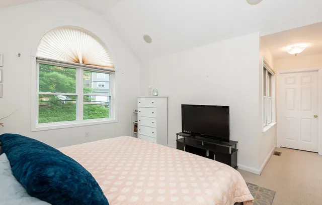 a bedroom with a bed and a flat tv screen on dresser
