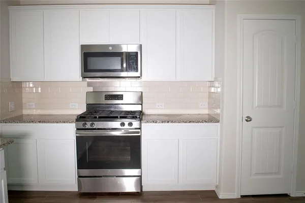 a kitchen with granite countertop a stove and a microwave