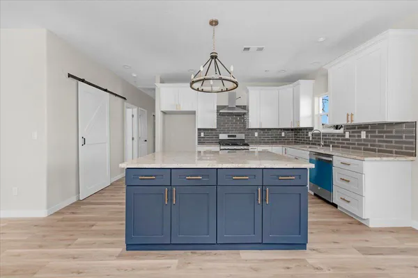 a kitchen with stainless steel appliances granite countertop a stove a sink dishwasher and a refrigerator with wooden floor