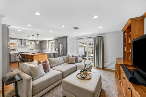 a living room with furniture kitchen view and a flat screen tv