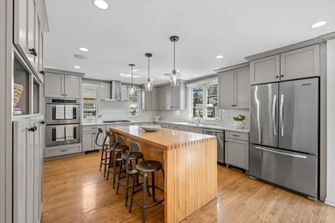 a kitchen with stainless steel appliances granite countertop a refrigerator a sink dishwasher a stove and a refrigerator with wooden floor