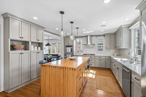 a large kitchen with kitchen island granite countertop a sink a counter space stainless steel appliances and cabinets