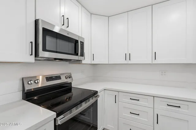 a kitchen with white cabinets and black appliances