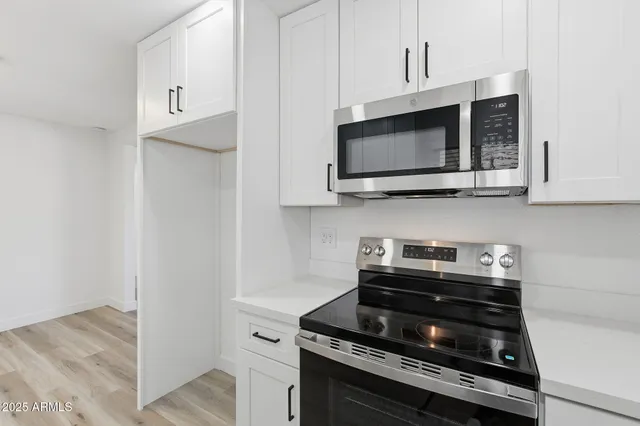 a kitchen with stainless steel appliances granite countertop white cabinets stove top oven and sink