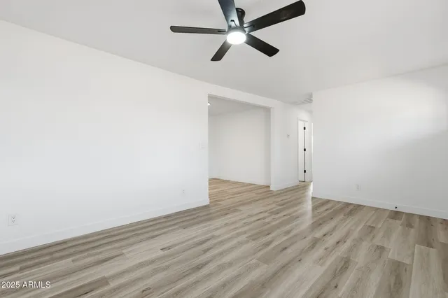 an empty room with wooden floor and a ceiling fan