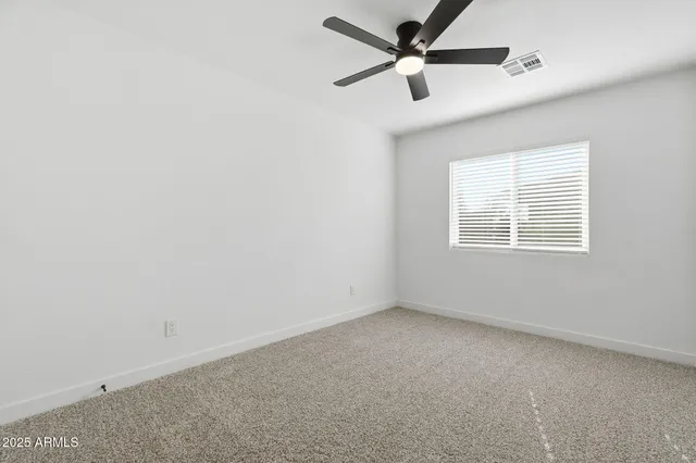 an empty room with a window and a fan