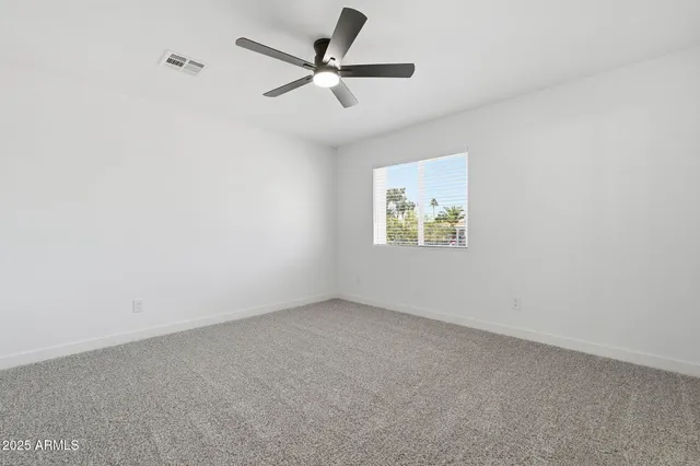 an empty room with a window and a ceiling fan