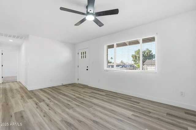 a view of empty room with wooden floor and fan