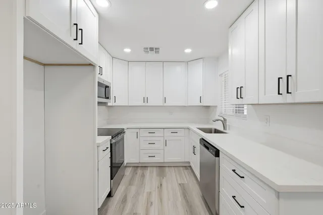 a kitchen with cabinets stainless steel appliances a sink and wooden floor