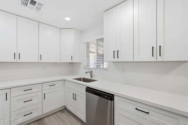 a kitchen with white cabinets and sink