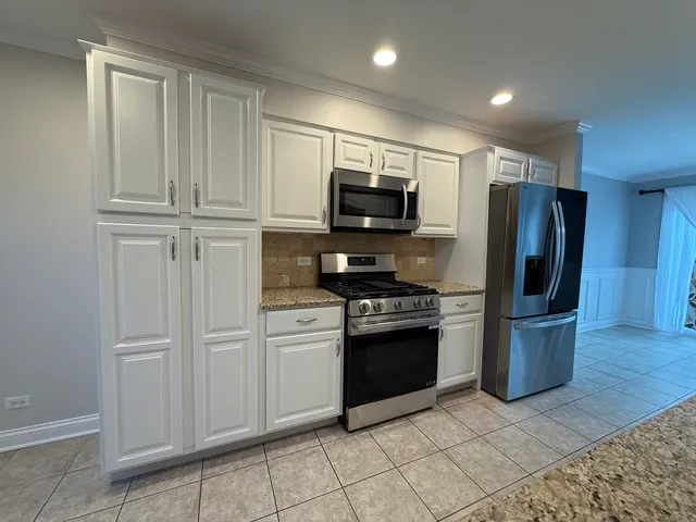 a kitchen with stainless steel appliances granite countertop a refrigerator and a stove top oven