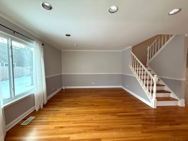 a view of an empty room with wooden floor and windows