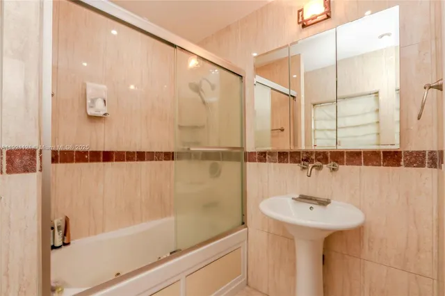 a bathroom with a sink and mirror with bathtub