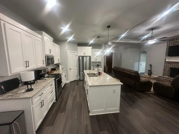 a large white kitchen with lots of counter top space a sink a stove and a refrigerator