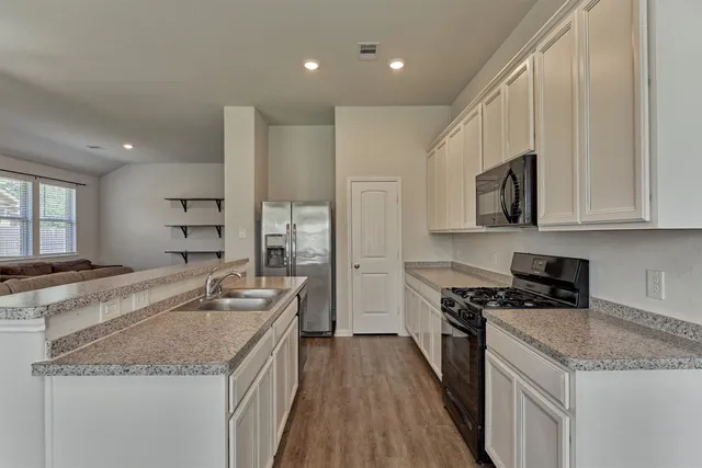 a kitchen with stainless steel appliances granite countertop a sink stove and refrigerator
