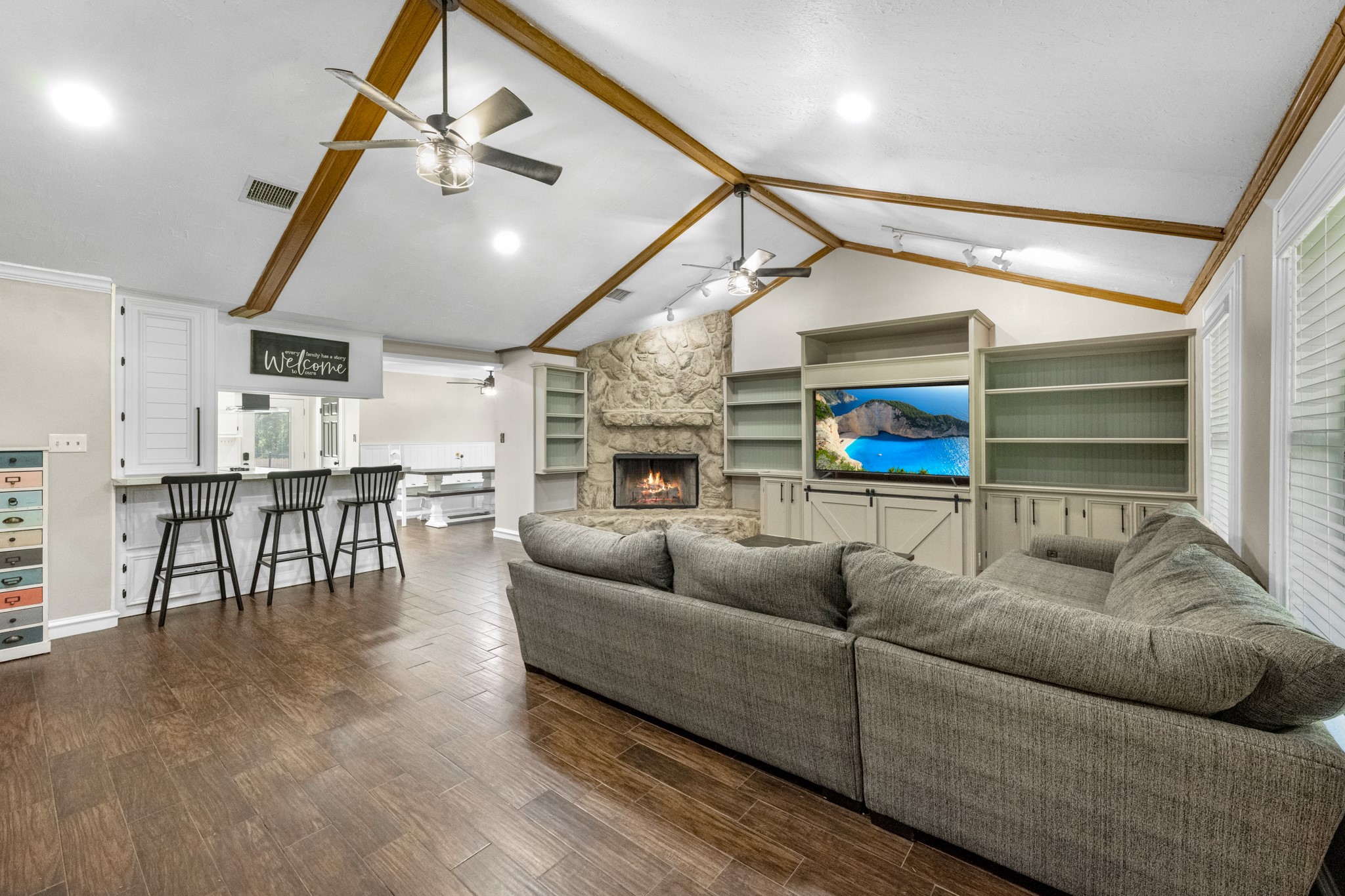 Spacious family room with vaulted ceiling, exposed beams, built-ins & stone-surround fireplace!