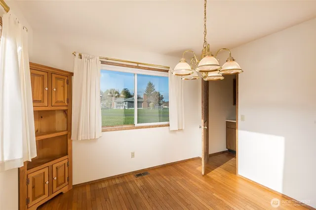 a view of a room with wooden floor chandeliers and kitchen view