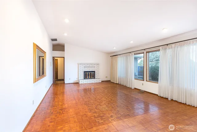 a view of an empty room with window and wooden floor