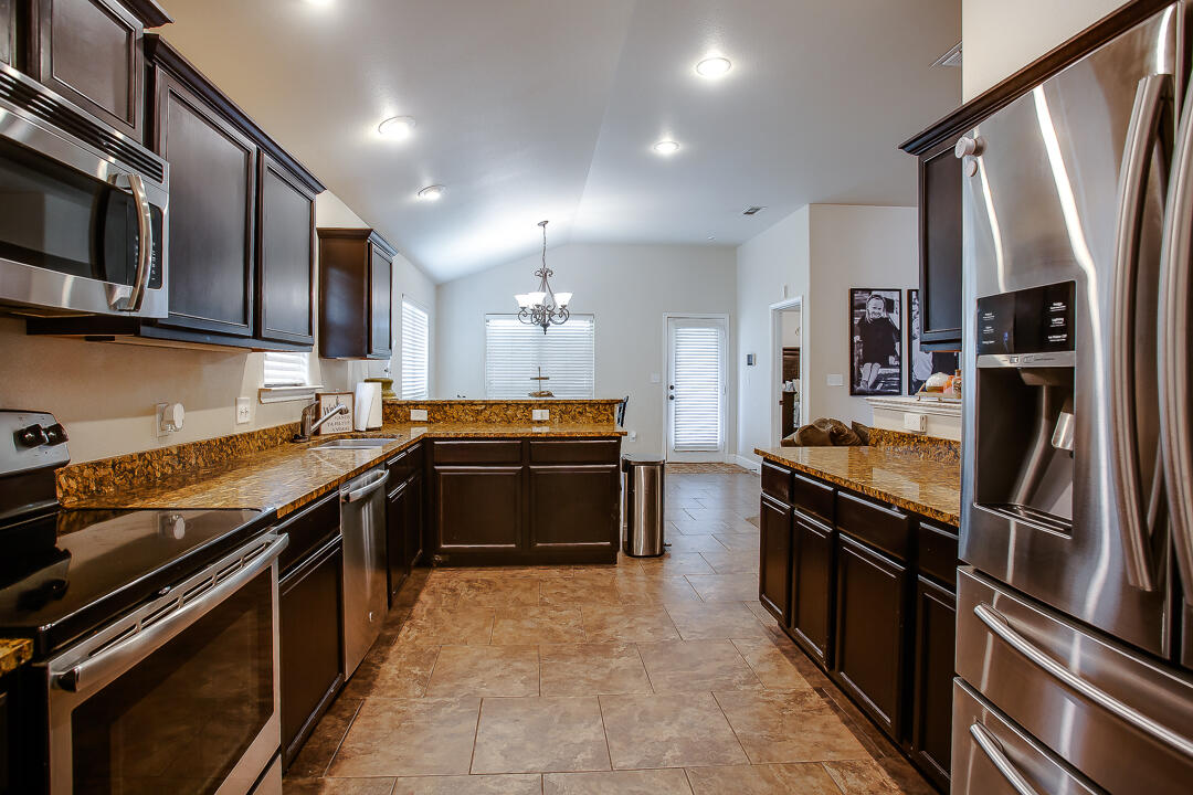 8804 Rochester Avenue Lubbock, TX 79424 - Photo 9 of 18 a kitchen with stainless steel appliances granite countertop a stove and a refrigerator