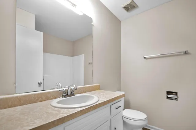 a bathroom with a granite countertop sink a mirror and a toilet