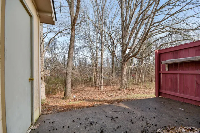 a backyard of a house with trees and wooden fence
