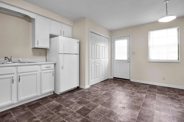 a view of a kitchen with a sink dishwasher a refrigerator and cabinets