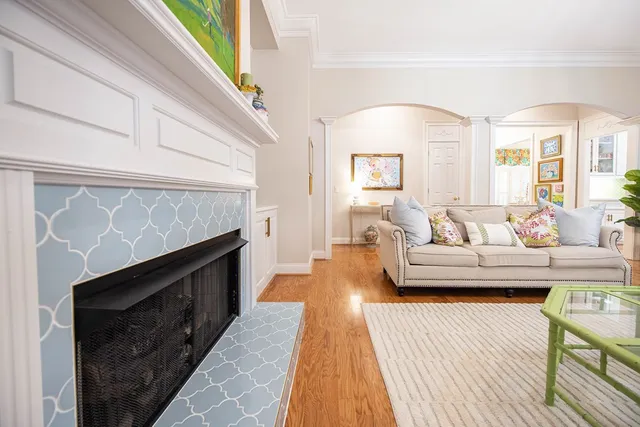 a spacious white kitchen with granite countertop a stove a sink a dining table and chairs with wooden floor
